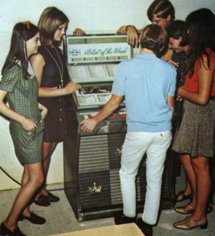 Group of six yoiung people crowded around a Jukebox. Possibly late '60s / early '70simage.