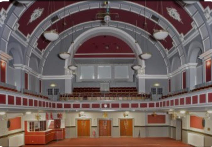 Inside Clydebank Town Hall. Big decorative arches against a reddish coloured dome ceiling.
