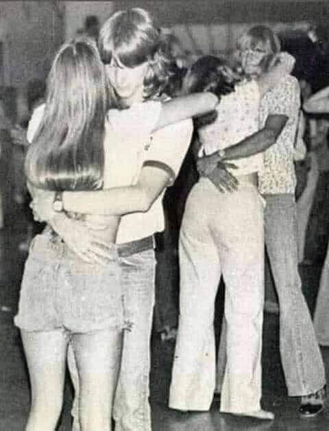 B/w image of teenage couples dancing a slow dance in the 1970s.