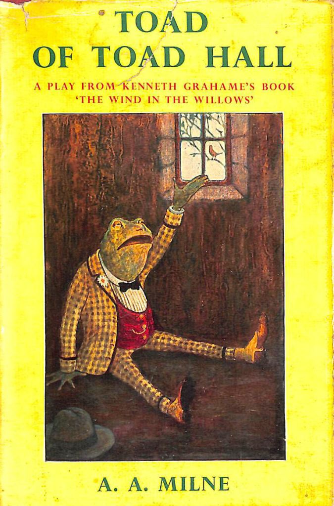 Book cover - 'Toad of Toad Hall' by A.A. Milne. Book cover is principally yellow in colour with green writing and features an image  of a toad  dressed in a checked, yellow suit, with a red waistcoat, sitting by a window.